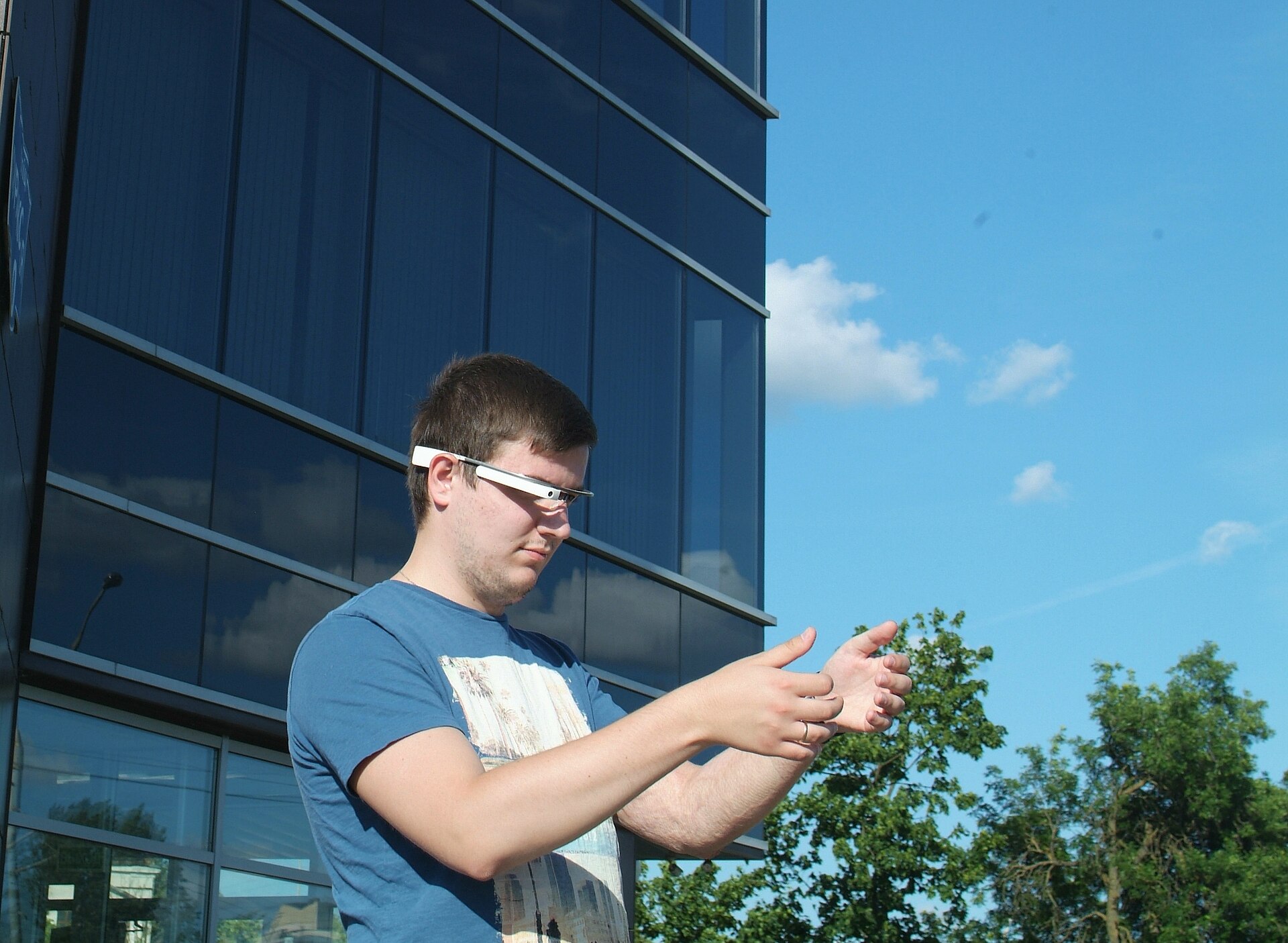 Person outdoors wearing early smart glasses and gesturing — AR wearables sit against skin for hours