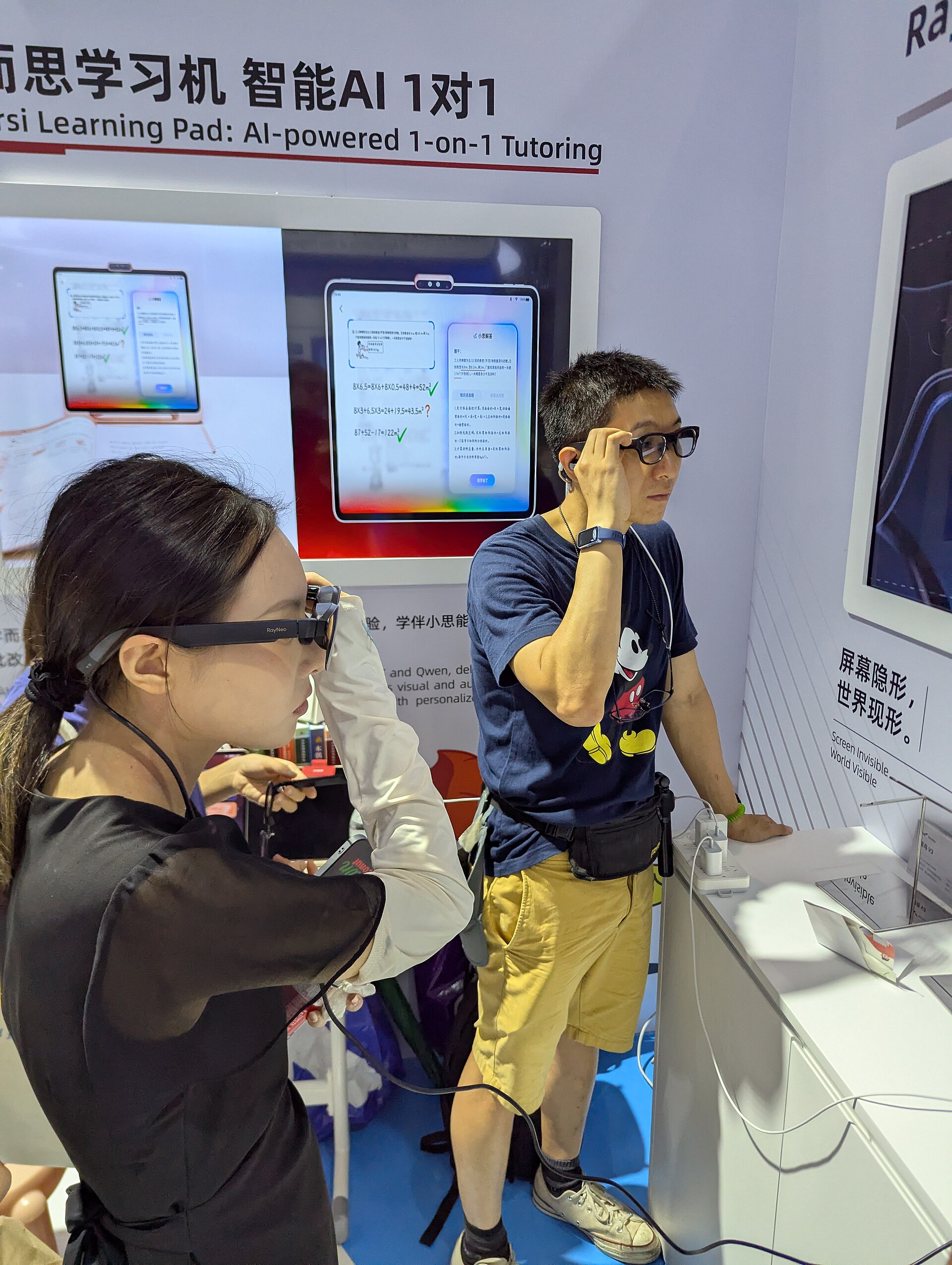 Attendees try modern thick-frame smart glasses at a trade show booth