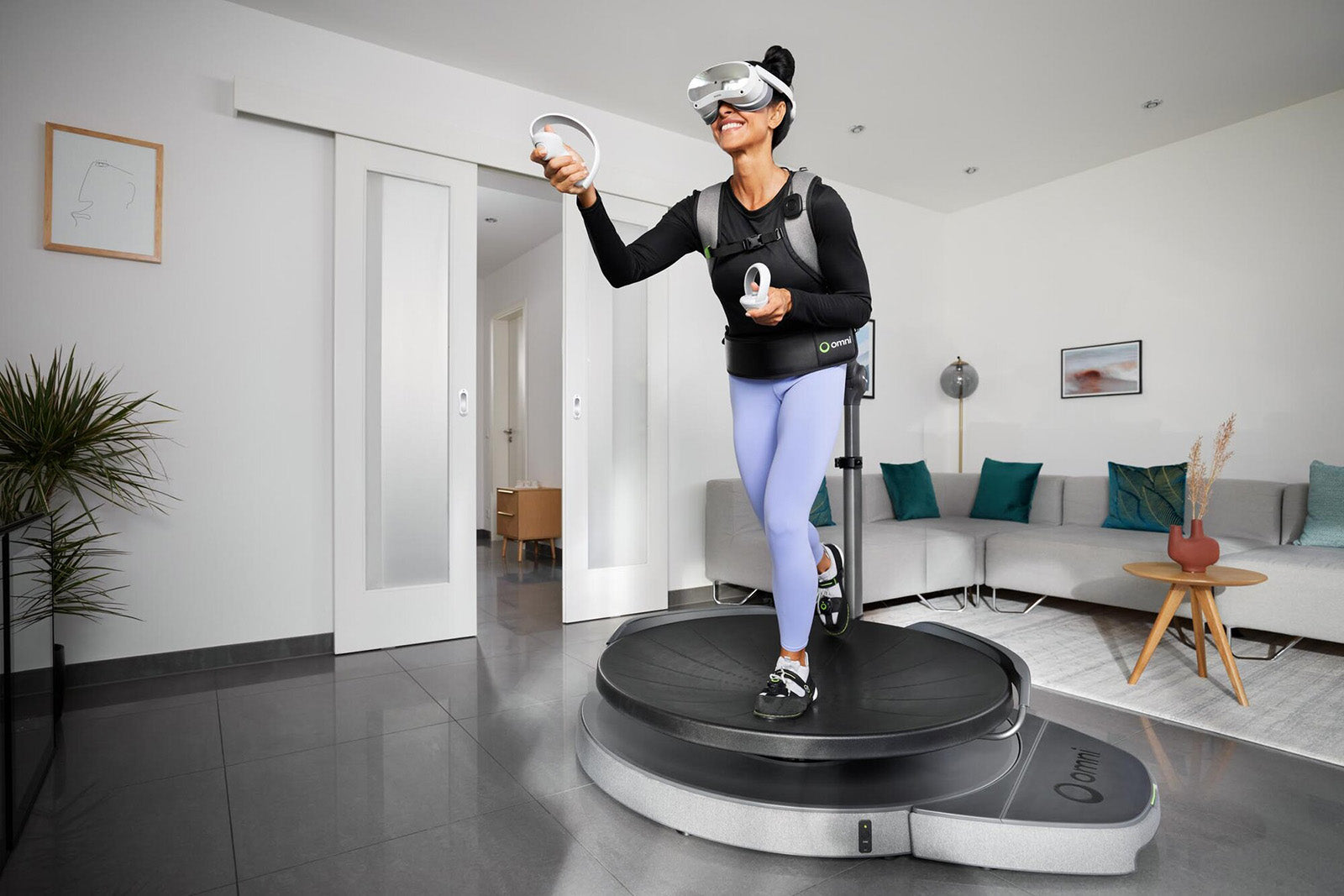 Person walking on Virtuix Omni One VR treadmill in a living-room setup