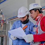 Construction workers review plans on an industrial job site — the hands-busy setting Inspecs and Qualcomm are targeting with AI safety glasses