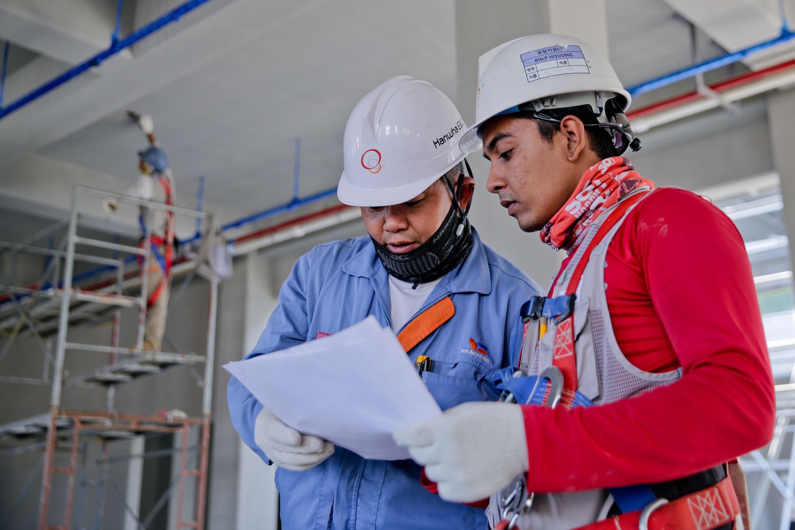 Construction workers review plans on an industrial job site — the hands-busy setting Inspecs and Qualcomm are targeting with AI safety glasses