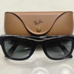 Black Ray-Ban Meta Gen 1 smart glasses in front of a brown leather charging case