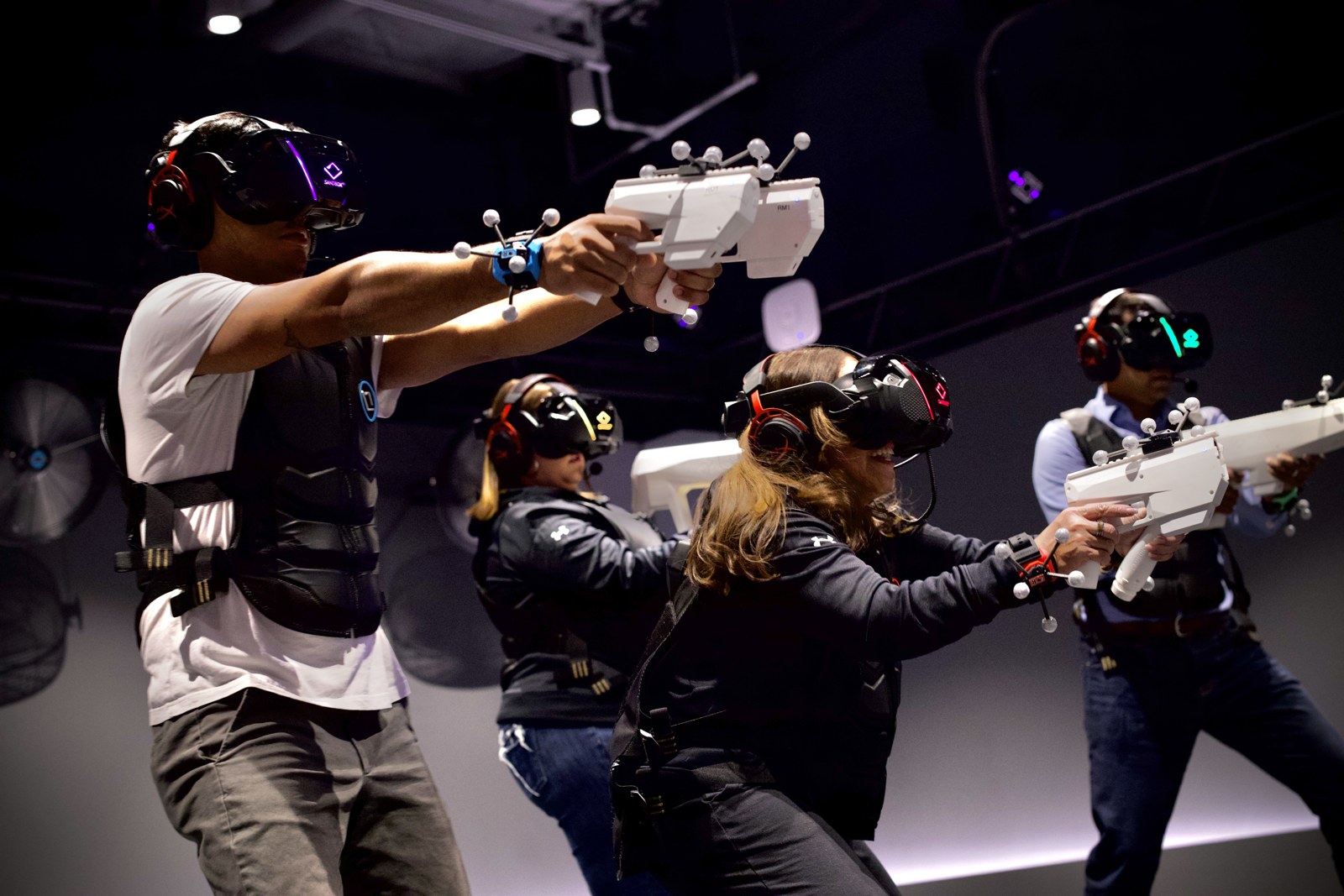 Players in a Sandbox VR arena with tracked rifle peripherals
