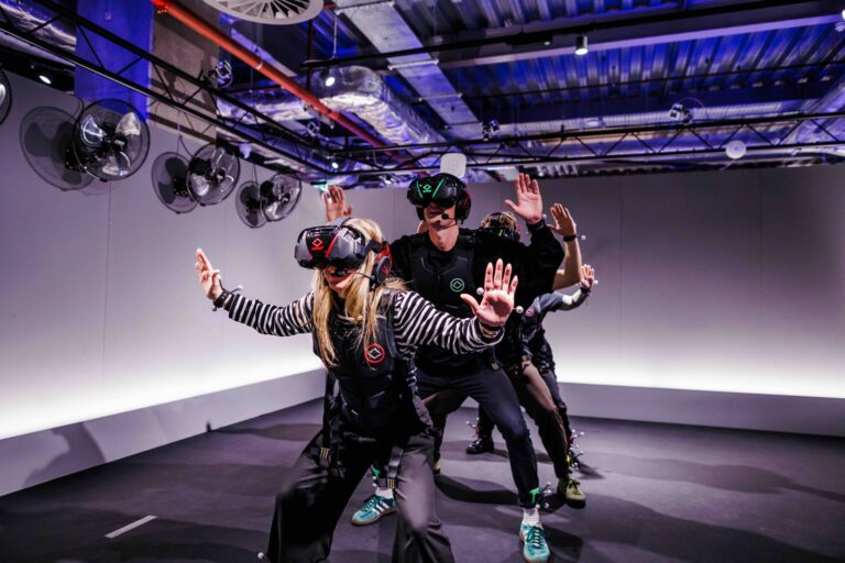 Guests in Sandbox VR free-roam kits with headsets, haptic vests, and full-body tracking markers