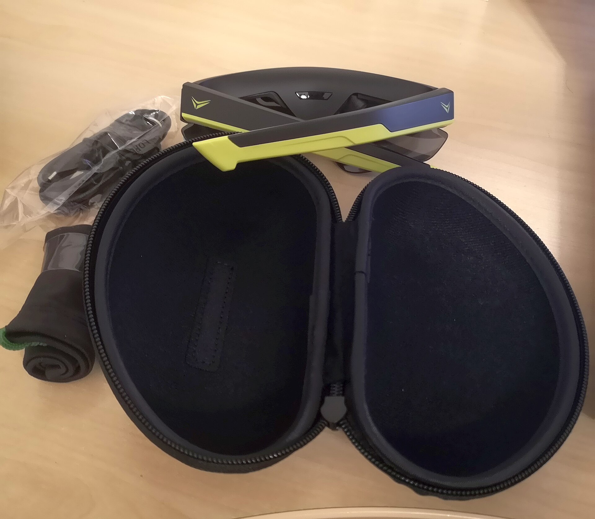Smart glasses with thick temple arms and case laid out — temples house batteries and radios that can run hot under load