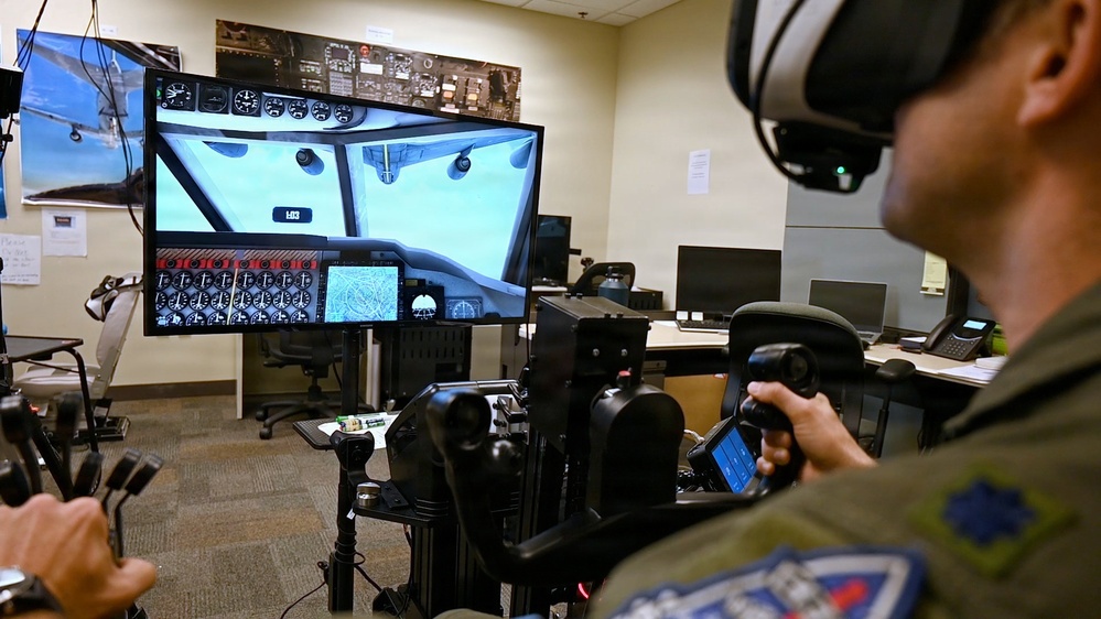 A pilot flies a simulated refueling approach on the EARL VR trainer while a monitor shows the headset view to instructors