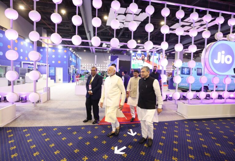 Visitors walking through the Jio pavilion at India Mobile Congress 2022 in New Delhi, with a large illuminated Jio logo