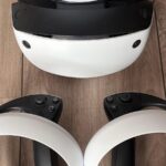 Sony PlayStation VR2 headset and two PS VR2 Sense controllers on a wooden floor