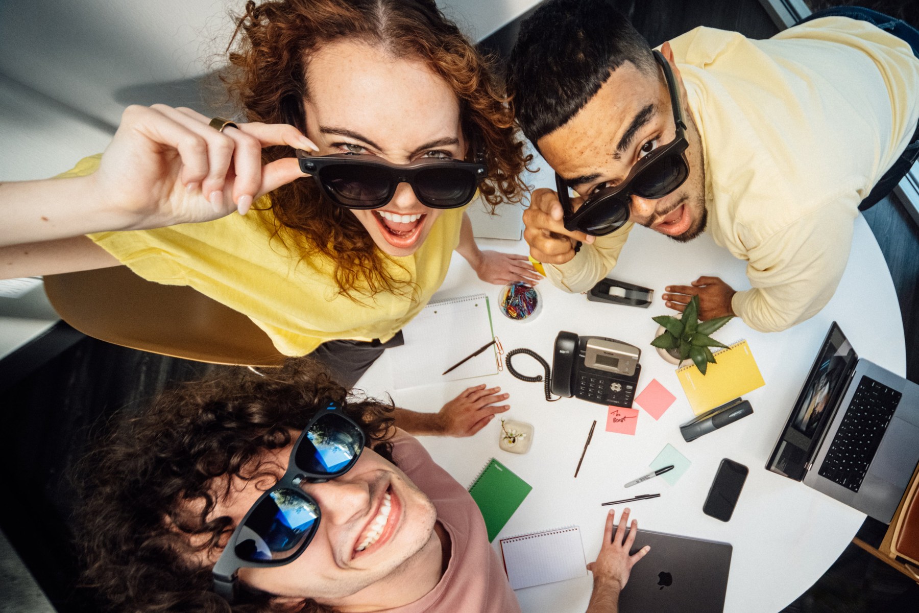 Three people wearing Viture Beast XR glasses around an office desk, overhead lifestyle shot